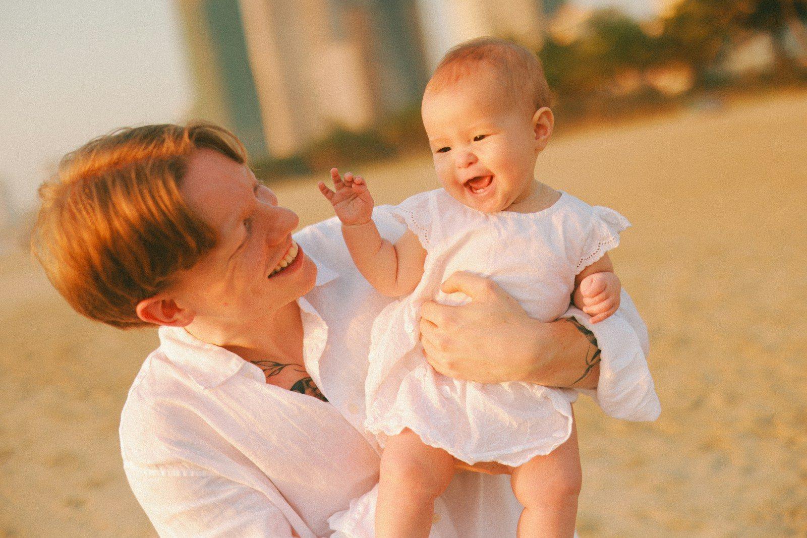 Father holding laughing baby on beach